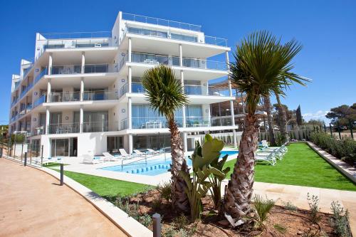 科洛尼亚圣霍尔迪Apartaments Posidonia的一座白色的大建筑,设有游泳池和棕榈树
