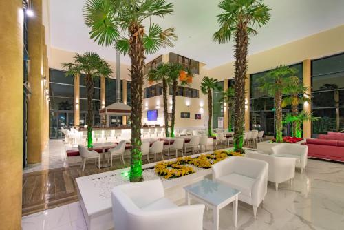 普里莫尔斯科Hotel Perla Beach Luxury - All Inclusive & Free Beach Access的大堂种植了棕榈树,配有桌椅
