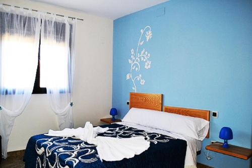 萨尔萨德格拉纳迪利亚Casa El lince de Granadilla, Norte provincia Cáceres, WIFI, Parque infantil, HIDROMASAJE, garaje, LAVAVAJILLAS的一间卧室配有一张蓝色墙壁的床和一扇窗户