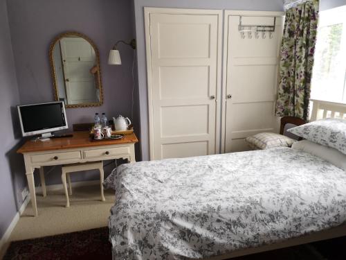 塞文欧克斯UPTHEDOWNS B&B的一间卧室配有一张床和一张带镜子的书桌