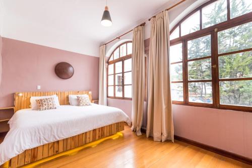 基多Viajero Quito Hostel的一间卧室设有一张大床和大窗户