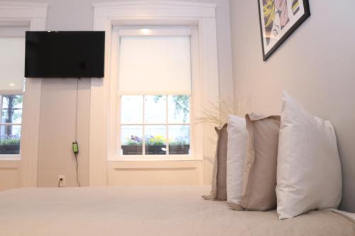 波士顿Downtown Beacon Hill, Convenient, Comfy Studio #1的一间卧室配有带枕头的床铺和电视。