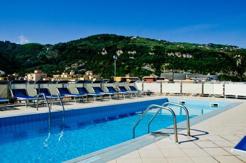 索伦托切萨雷奥古斯托大酒店的一个带蓝色椅子的游泳池和一个山