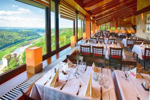 洛门巴斯蒂博格酒店的餐厅设有白色的桌椅和大窗户。