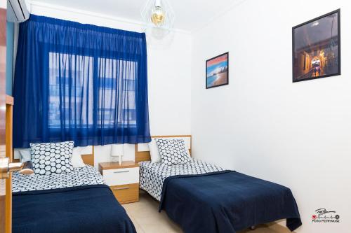 阿利坎特Apartament Solar的一间卧室配有两张床和蓝色窗帘
