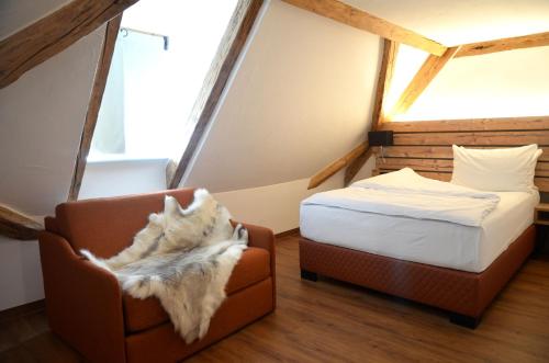 乌尔姆Am Zehntstadl Hotel & Sauna的一间卧室,卧室内配有一张床和一把椅子