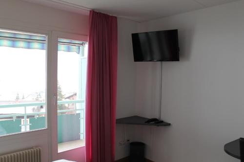 达沃斯Bernina Bed and Breakfast的一间配有电视和红色窗帘的房间