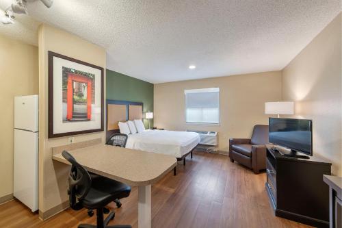 夏洛特Extended Stay America Select Suites - Charlotte - Tyvola Rd - Executive Park的酒店客房设有一张床、一张书桌和一台电视机。