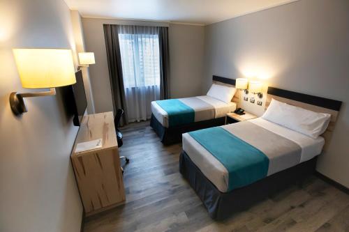 维纳德马Hotel Diego de Almagro Viña del Mar的酒店客房设有两张床和窗户。