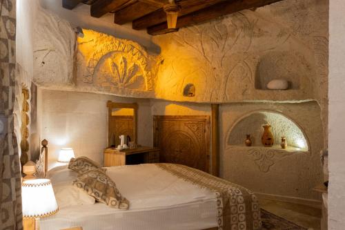 格雷梅Grand Elite Cave Suites的一间卧室配有一张床,墙上挂有绘画作品