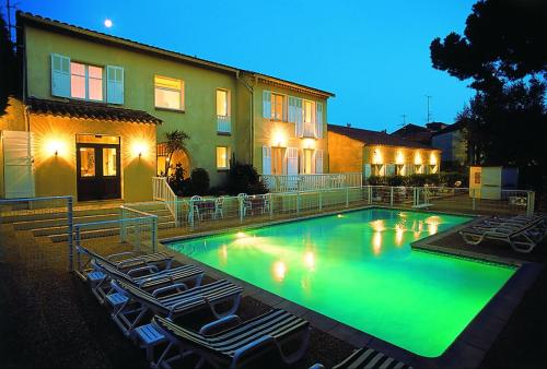 圣马克西姆卢宝乌瓦杜酒店的一座大楼前的游泳池,配有躺椅