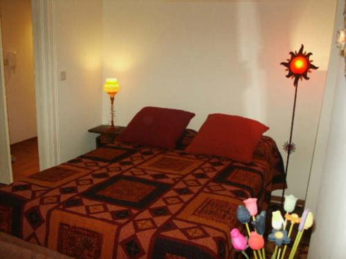 里斯本上城区卡萨斯酒店的一间卧室配有一张带红色枕头和鲜花的床