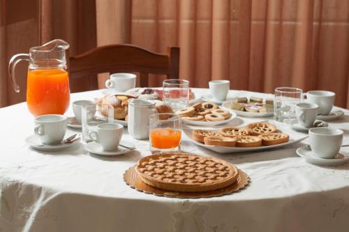 皮亚扎-阿尔梅里纳B&B Villa Roma的一张桌子,上面有白色的桌布,上面有饼干和橙汁