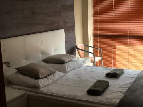 奥克宁卡Komfortowe Apartamenty的一张带两个枕头的床和一把靠窗的椅子