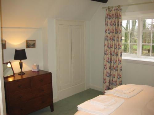 沃明斯特Job's Mill Cottage的一间卧室配有一张床、一个梳妆台和一扇窗户。