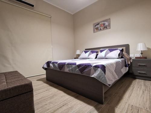 贝鲁特West House Apartments-Mar Mikhael的一间卧室配有一张大床,铺有紫色和白色的床单。