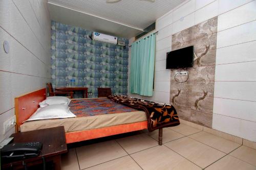 贾朗达尔National Guest House的一间卧室配有一张床和一台电视。