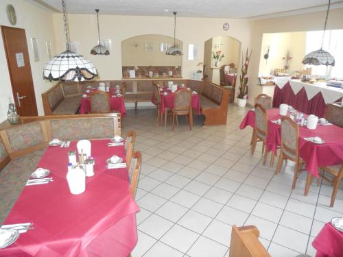 美因茨甘尼安和臣伯格酒店的餐厅配有桌椅和红色桌布