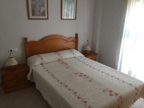 安波拉Precioso apartamento cerca de la playa的一间卧室配有一张带白色棉被和红色鲜花的床。
