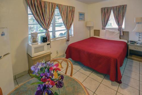 哈兰代尔海滩Richard's Motel Extended Stay的配有床和鲜花桌的酒店客房
