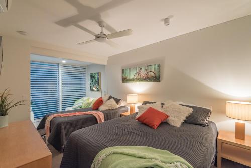 努萨维尔Anchorage - Riverfront Luxury on Gympie Terrace的一间卧室配有两张床和吊扇