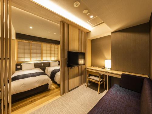 京都Hotel Elcient Kyoto Hachijoguchi的一间卧室配有一张床和一张书桌及电视