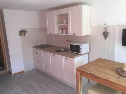 拉瓦罗内Appartamento Dalma Foresta的厨房配有白色橱柜、水槽和桌子