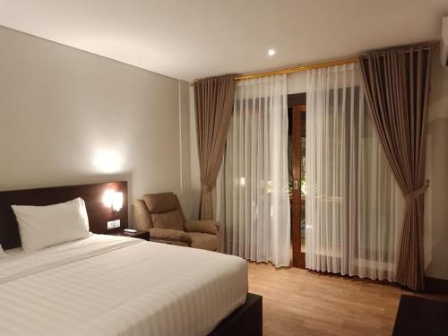 库塔苏里亚库塔别墅的配有一张床和一把椅子的酒店客房