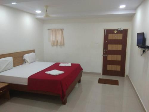库姆巴科纳姆Raya's Inn的一间卧室配有一张带红色毯子的床