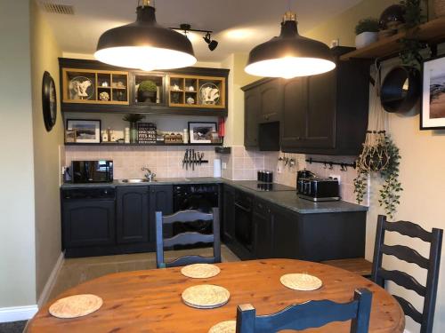 班多伦Sandy Cove Bundoran Sea Views Free Wifi Netflix Luxurious Apartment的一间带木桌的厨房和一间带黑色橱柜的厨房