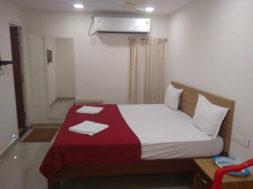 库姆巴科纳姆Raya's Inn的一间卧室配有一张床铺,床上铺有红色毯子