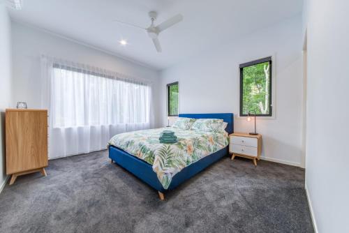 埃尔利海滩Hillside Haven - Airlie Beach的一间卧室设有蓝色的床和窗户。