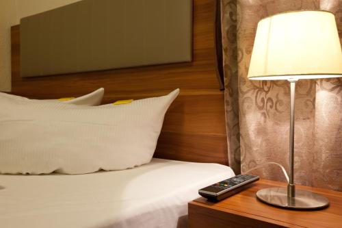 美因河畔法兰克福动物园竞技场酒店的一张带台灯的床和一张桌子上的遥控器