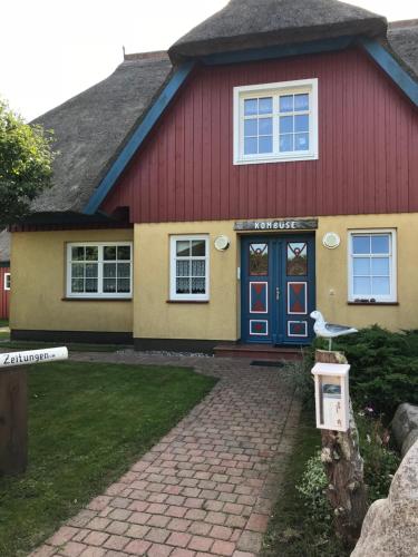 博恩"Bootsmannskammer" by Ferienhaus Strandgut的蓝色门的红色和黄色房子