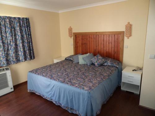 阿尔布费拉VilaBranca的一间卧室配有一张带木制床头板的床