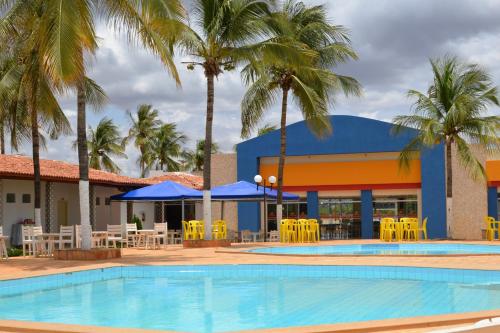 IrecêFiesta Bahiana Club Hotel的酒店前方的游泳池配有椅子和遮阳伞