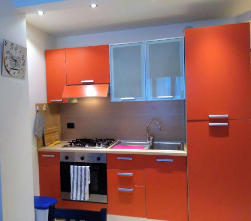 皮特拉利古Appartamento Angela的厨房配有橙色橱柜、水槽和炉灶。