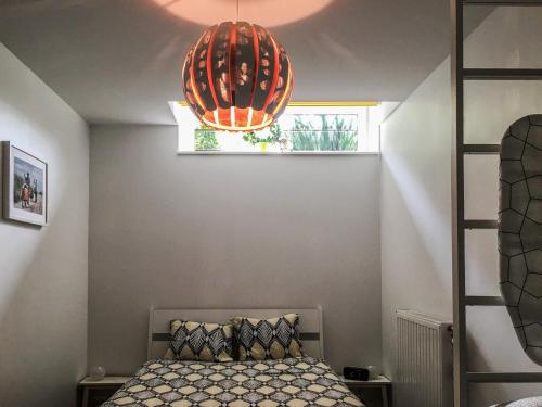TilffLoft lumineux Tilff-Liège的一间卧室配有一张床和一个大型橙色吊灯