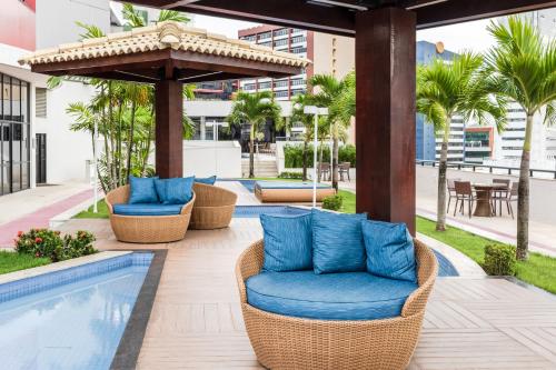萨尔瓦多Mercure Salvador Boulevard Hotel的一个带藤椅的庭院和一个游泳池