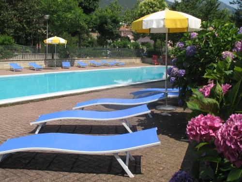 科哥莱托皮内塔酒店的游泳池旁的三把躺椅和一把遮阳伞