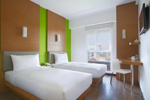 泗水昂泵马朗泗水阿利斯酒店的绿墙客房的两张床