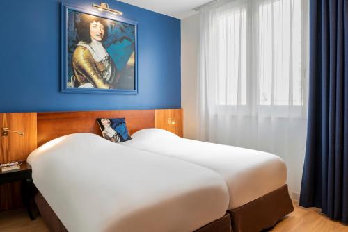 凡尔赛Hotel des Lys的卧室配有一张大床,墙上挂有绘画作品