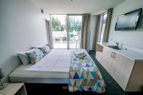 皇后镇Nomads Queenstown Hostel的客房设有带水槽的床和电视。