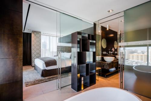 迪拜The Canvas Dubai - MGallery Hotel Collection的一间卧室配有一张床,浴室设有水槽
