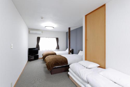金泽Hummingbird Kanazawa的酒店客房设有三张床和窗户。