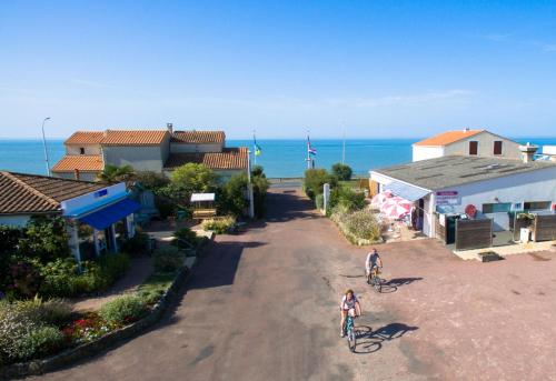 滨海圣帕莱Camping Le Puits de l'Auture的两个人骑着自行车沿着靠近大海的公路行驶