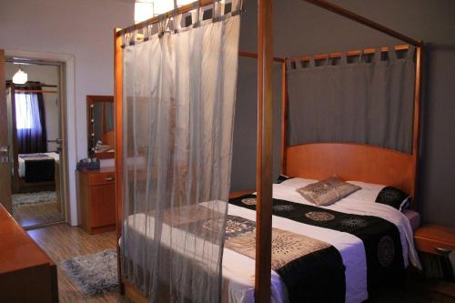圣保罗湾城Sunny Lodge Apartment的一间卧室配有四柱床和镜子