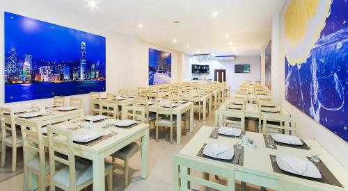 里奥阿查Ribai Hotels -Riohacha的餐厅设有白色的桌椅和大型壁画