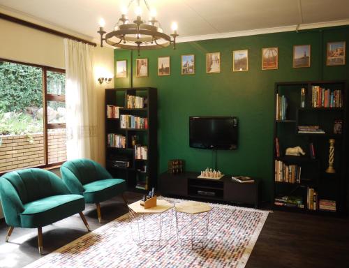约翰内斯堡可莱桑顿豪华宾馆的绿色的客厅配有两把椅子和电视
