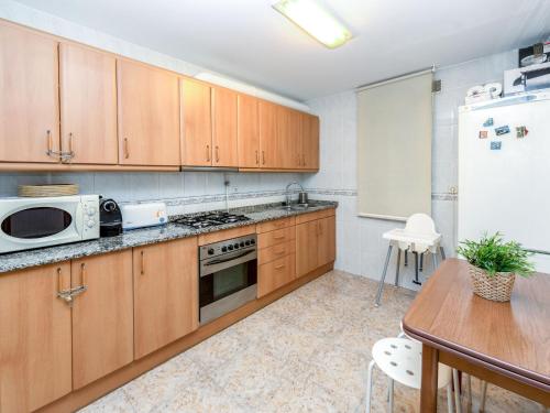 巴塞罗那Apartment Camp Nou- Travessera de les Corts by Interhome的厨房配有木制橱柜、桌子和冰箱。